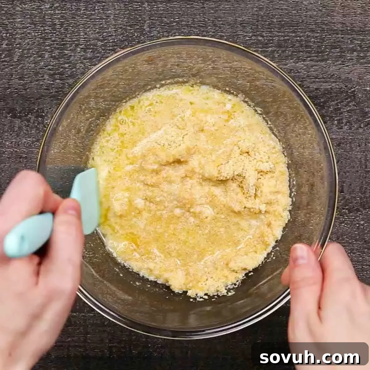A hand mixing Ritz cracker crumbs, melted butter, and pineapple juice in a small bowl to create the casserole topping.