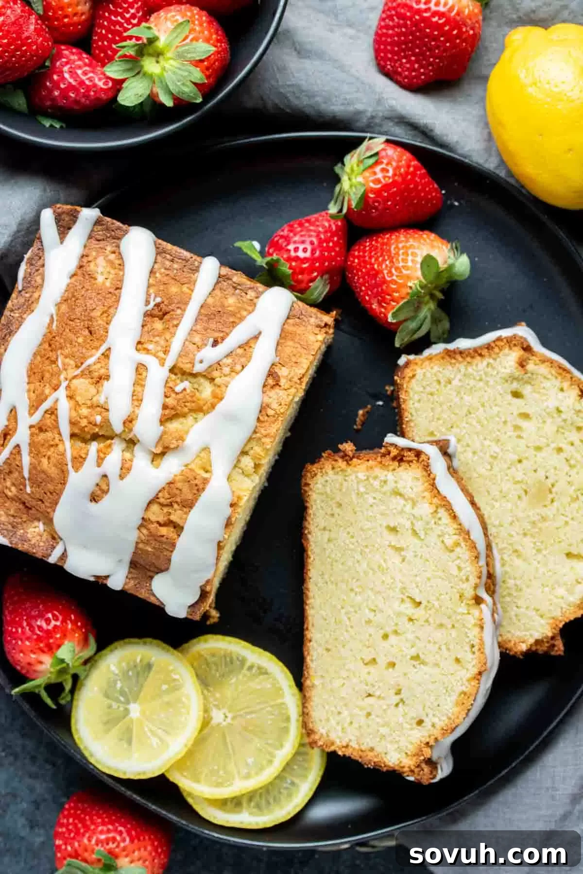 A pristine slice of lemon pound cake with fresh strawberries and lemon icing, ready to be enjoyed.