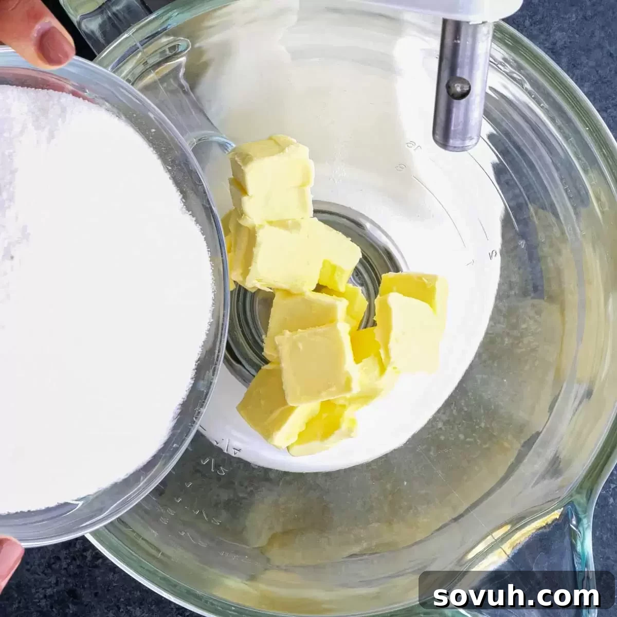 A person creaming room temperature butter and granulated sugar together in a stand mixer bowl.