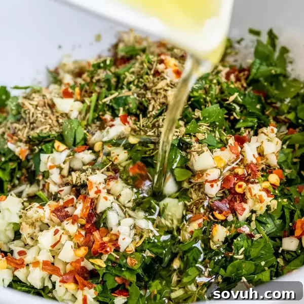 Whip Up Flavorful Chimichurri 3 Pouring olive oil into a bowl of fresh herbs and spices, the essential step in making vibrant Chimichurri sauce by hand.