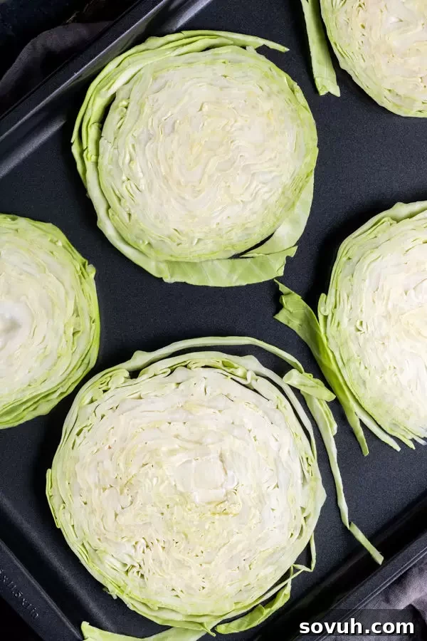 How to make healthy keto Oven Roasted Cabbage Steaks, showing raw slices on a baking sheet