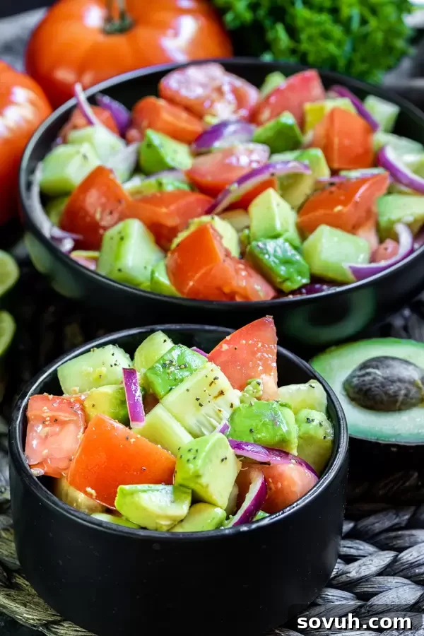 Various chopped fresh vegetables including cucumber, tomato, and red onion, ready to be mixed for the salad.