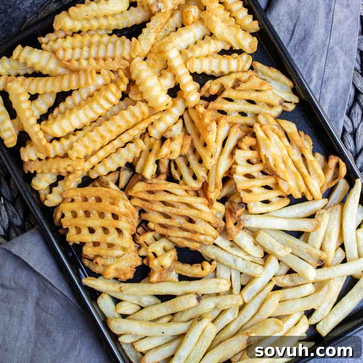 black sheet pan wit Air Fryer Frozen French Fries on gray cloth