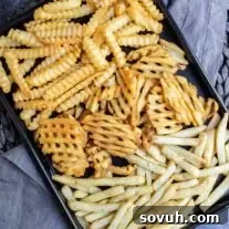 black sheet pan wit Air Fryer Frozen French Fries on gray cloth