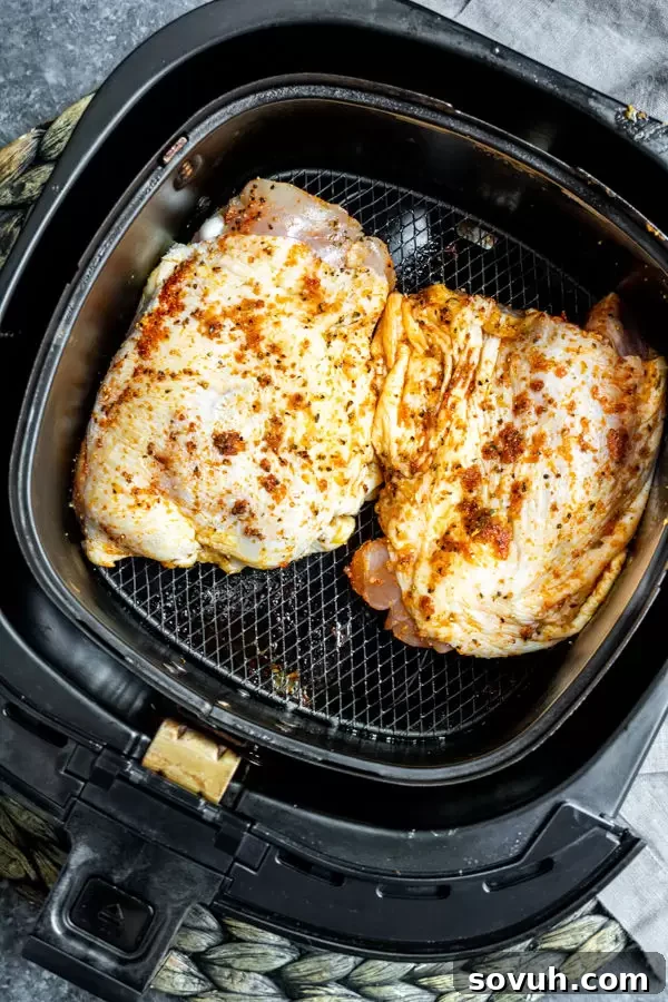 Crispy Air Fryer Chicken Thighs 4 Raw seasoned Air Fryer Chicken Thighs arranged in an air fryer basket.