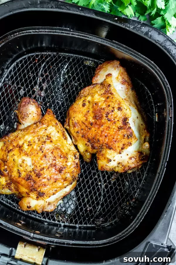Crispy Air Fryer Chicken Thighs 5 Crispy Air Fryer Chicken Thighs cooling in an air fryer basket after cooking.