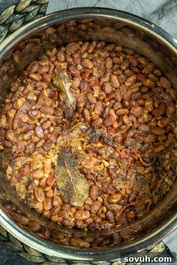 The Instant Pot lid sealed, with steam starting to release, indicating the pressure cooking process for the pinto beans is underway.