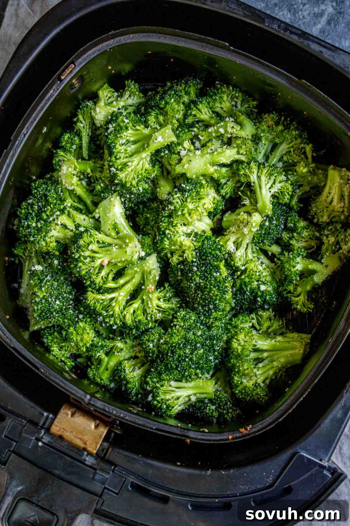 Perfectly cooked Air Fryer Broccoli in a black air fryer basket, ready to be served.