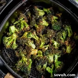 Air Fryer Broccoli with seasoning in an air fryer basket.
