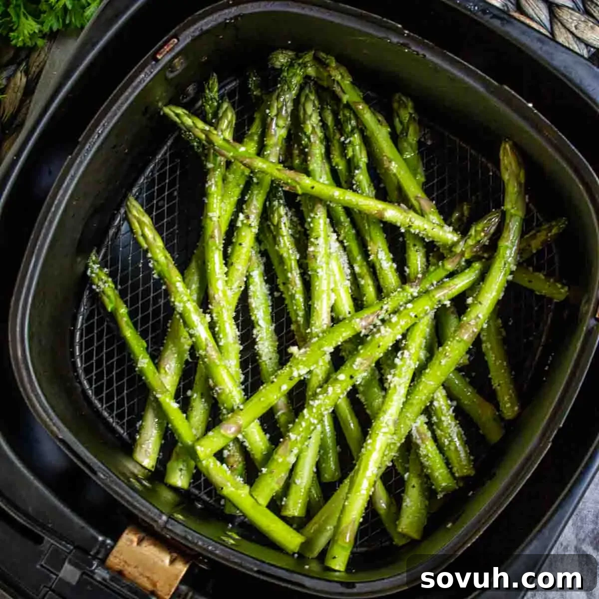 Air Fryer Asparagus with seasoning in an air fryer basket.