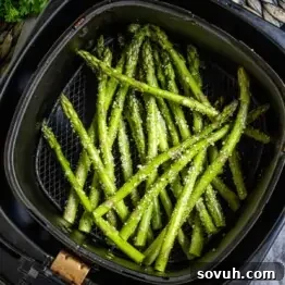 Air Fryer Asparagus with seasoning in an air fryer basket.