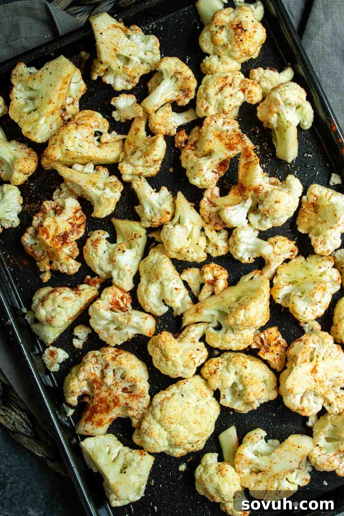Crispy Air-Fried Cauliflower Bites 3 Perfectly seasoned and roasted cauliflower florets in the air fryer, glistening with spices on a baking sheet.