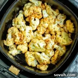 Roasted cauliflower florets in an air fryer basket.