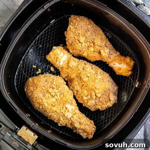 Crispy keto fried chicken pieces arranged in a single layer within an air fryer basket, ready for cooking to achieve a golden finish.