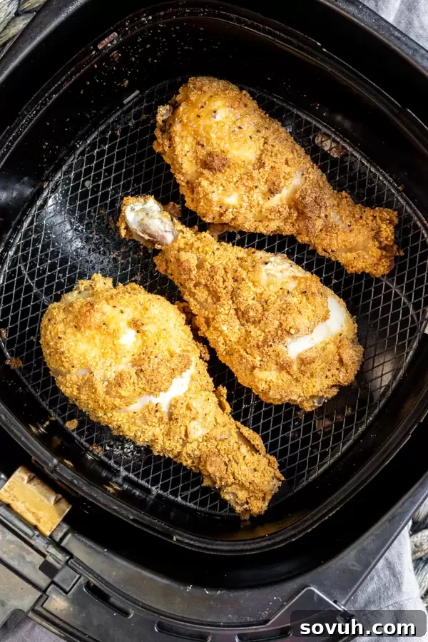 Close-up of golden brown Keto Fried Chicken drumsticks and thighs, freshly air-fried and perfectly crispy, resting in the air fryer basket.