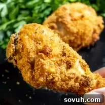 holding crispy Keto Fried Chicken drumstick