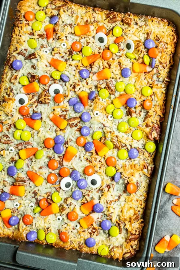 Halloween Magic Cookie Bars being baked in a rectangular pan, showing the golden brown crust and layers beginning to set.
