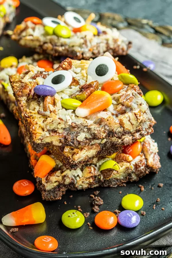 A stack of Halloween Magic Cookie Bars on a white plate, showcasing their thick layers and colorful candy toppings, ready to be enjoyed.