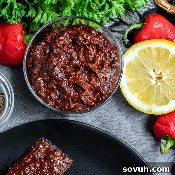 Close-up view of fresh homemade Harissa Paste in a small white cup, highlighting its thick, rich texture.
