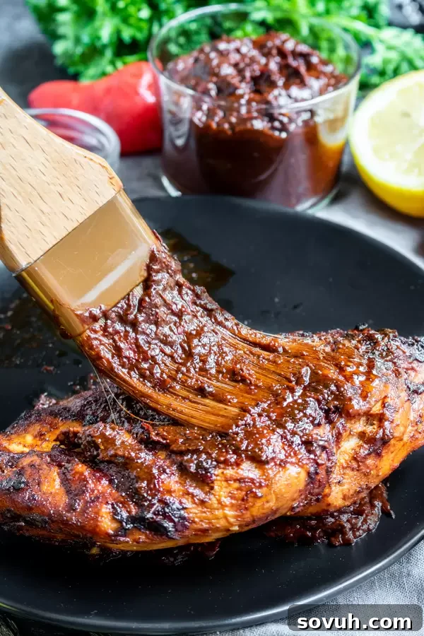 Harissa Paste lavishly spread on pieces of perfectly cooked chicken, illustrating its use as a delicious marinade.