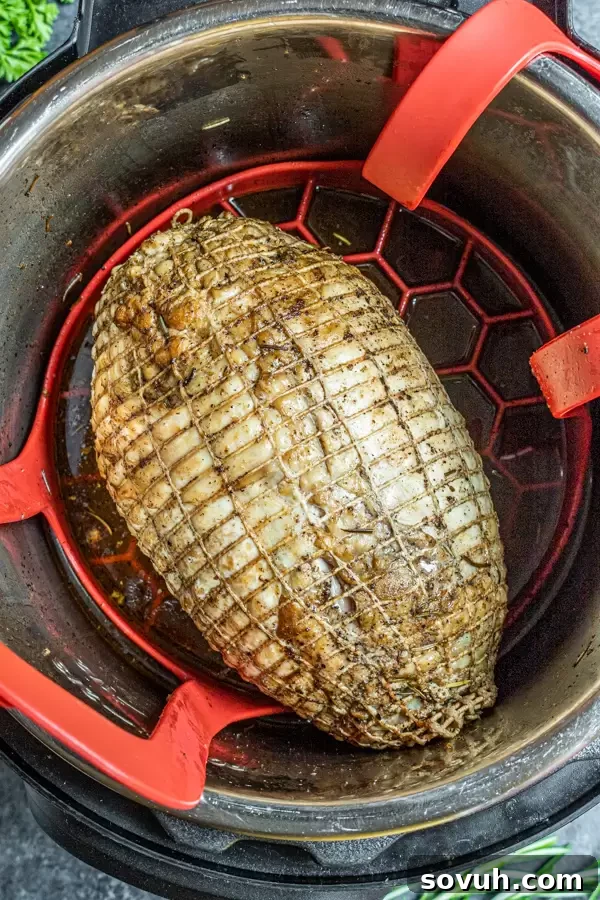 A boneless turkey breast, seasoned and seared, resting on a trivet inside an Instant Pot with chicken broth at the bottom, ready for pressure cooking.