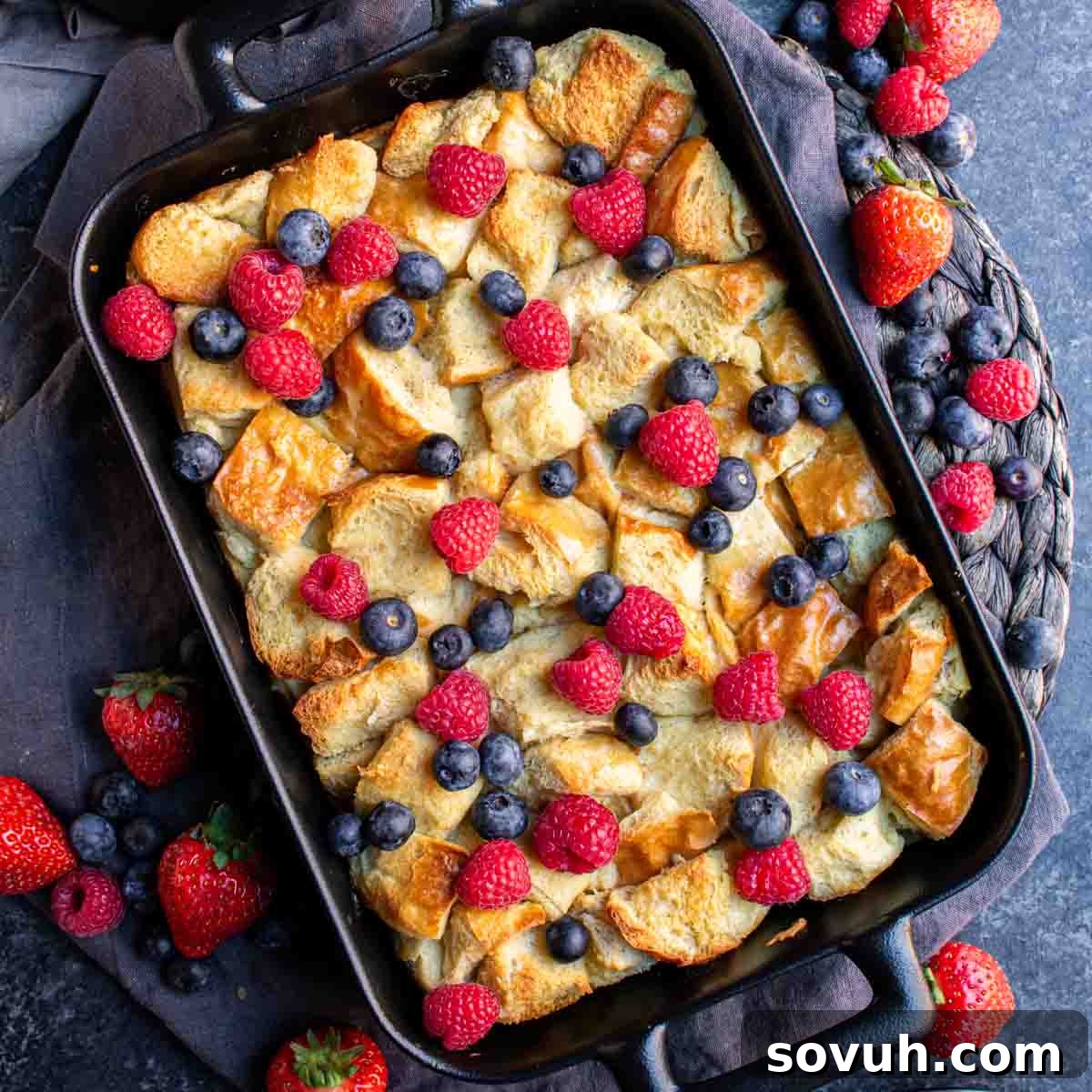 Overnight French Toast Bake with fresh berries and blueberries in a rustic cast iron pan.