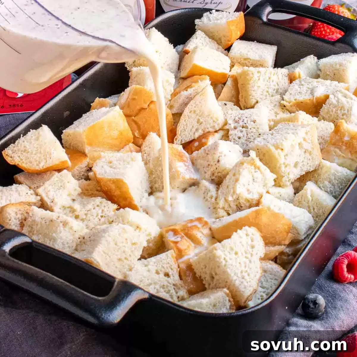 A casserole dish filled with bread cubes soaking in the rich egg and milk mixture, ready for the Overnight French Toast Bake preparation.