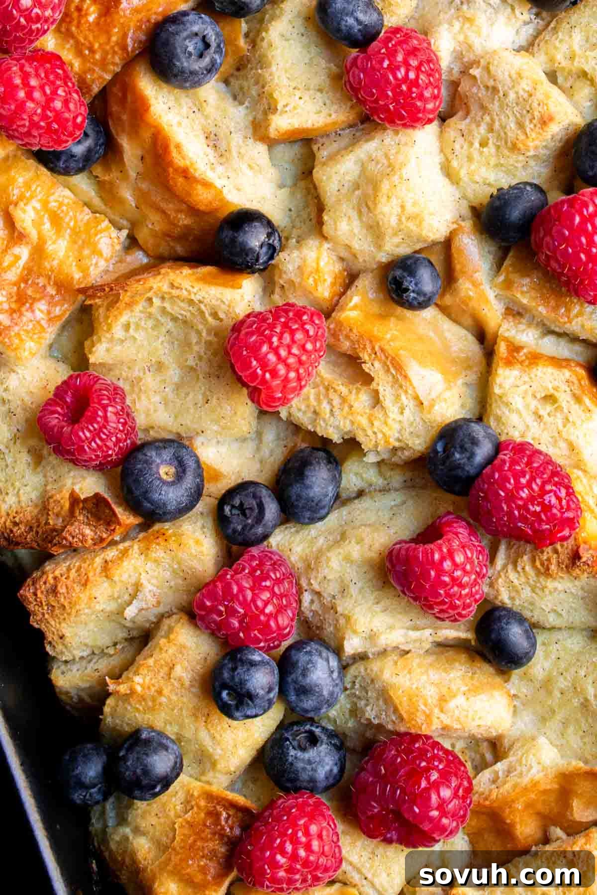 A vibrant display of French Overnight French Toast Bake, generously topped with an array of fresh berries and bright blueberries, highlighting its appeal.