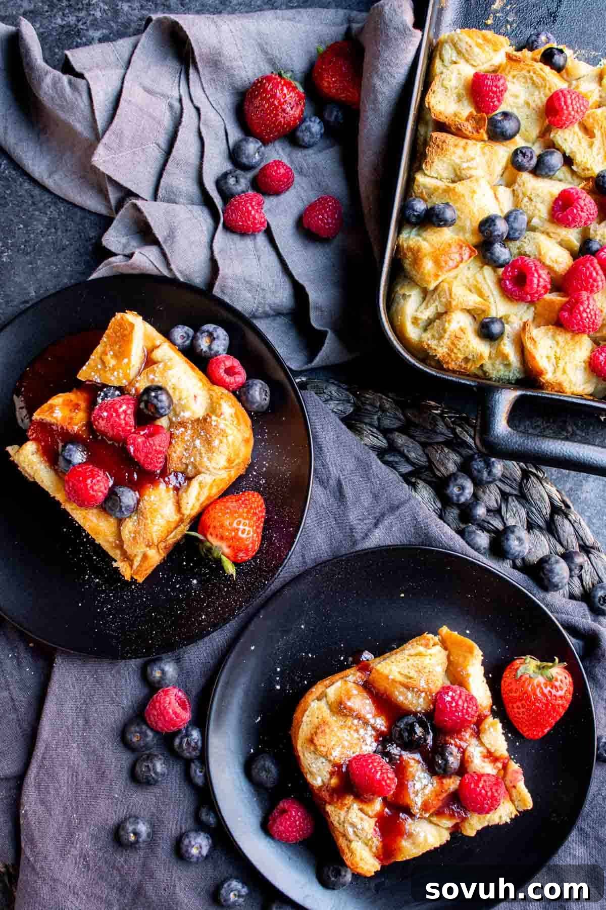 A delightful plate of Overnight French Toast Bake, garnished with an abundance of fresh berries and vibrant raspberries, ready to be enjoyed.