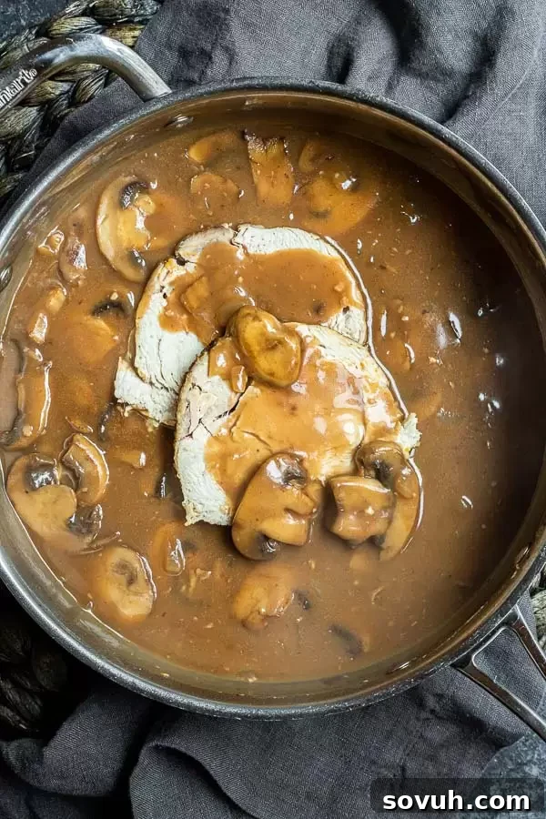 Succulent Turkey Marsala 4 Turkey Marsala simmering in a large stainless steel skillet, showcasing the tender turkey slices and browned mushrooms enveloped in a rich, glossy brown sauce.