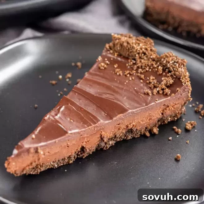 A slice of Decadent Chocolate Tart on a black plate, with a shiny chocolate glaze.