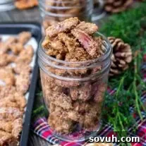 candied nuts in a mason jar with pine branch and plaid napkin