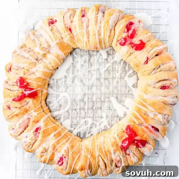 Top-down view of a golden-brown Holiday Crescent Roll Breakfast Ring, artfully shaped like a wreath and drizzled with white icing, ready for Christmas morning.