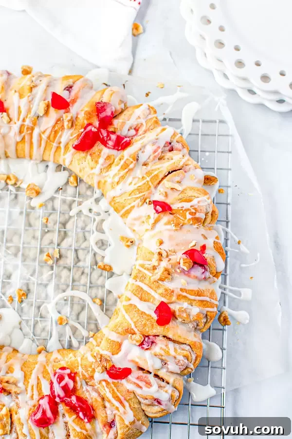 A golden-brown Holiday Crescent Roll Breakfast Ring resting on a wire cooling rack, glistening with a fresh glaze.