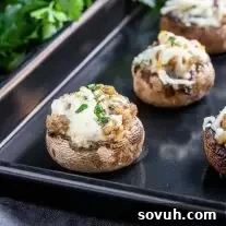 stuffed mushrooms with sausage on a black baking sheet
