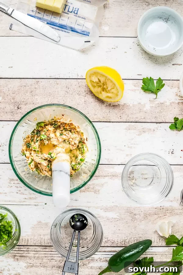 Seasoned herb butter mixture in a small bowl with a whisk, ready to be spread on lobster tails