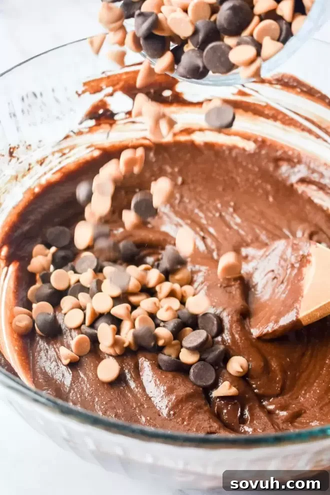 Adding dark chocolate chips and peanut butter chips to the rich brownie batter for extra flavor and texture.