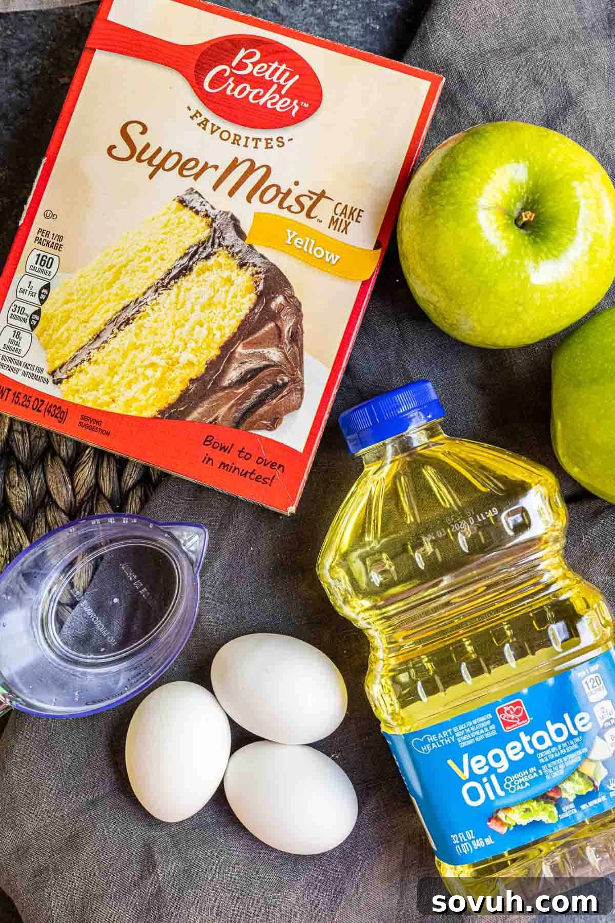 Ingredients for caramel apple cupcakes, including a box of yellow cake mix and Granny Smith apples