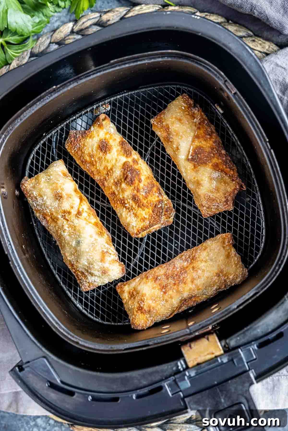 Crispy homemade Air Fryer Egg Rolls in an air fryer basket after cooking.