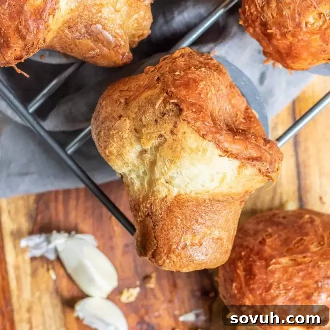 Golden brown Garlic Parmesan Popovers with garlic butter glistening, fresh from the oven, ready to be served as a delicious side dish.
