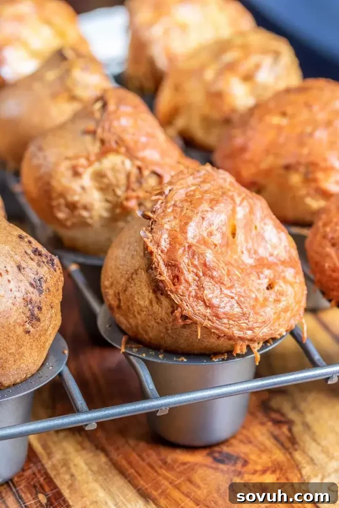 Close-up view of Garlic Parmesan Popovers baking in a specialized popover pan, showing their impressive golden-brown rise.