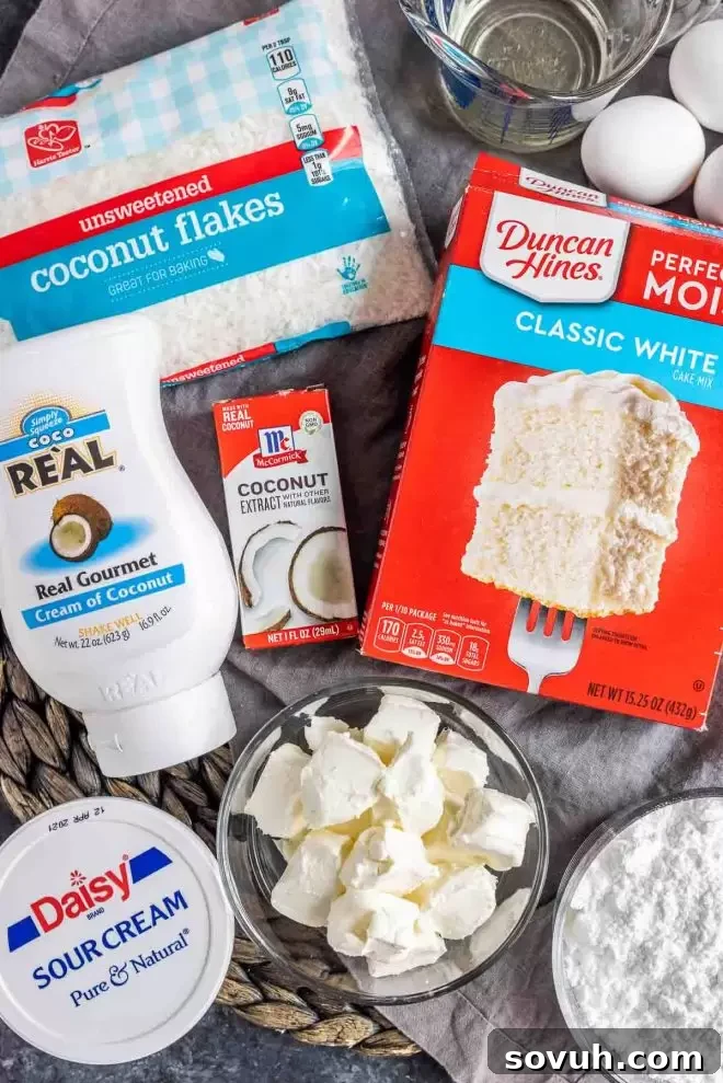 Various ingredients laid out for preparing Coconut Sheet Cake, including a cake mix box, eggs, sour cream, and cream of coconut.