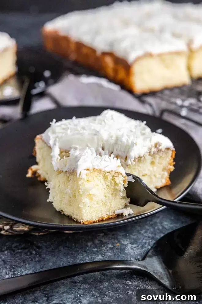 A delightful slice of Coconut Sheet Cake resting on a plate, with a fork poised for tasting.