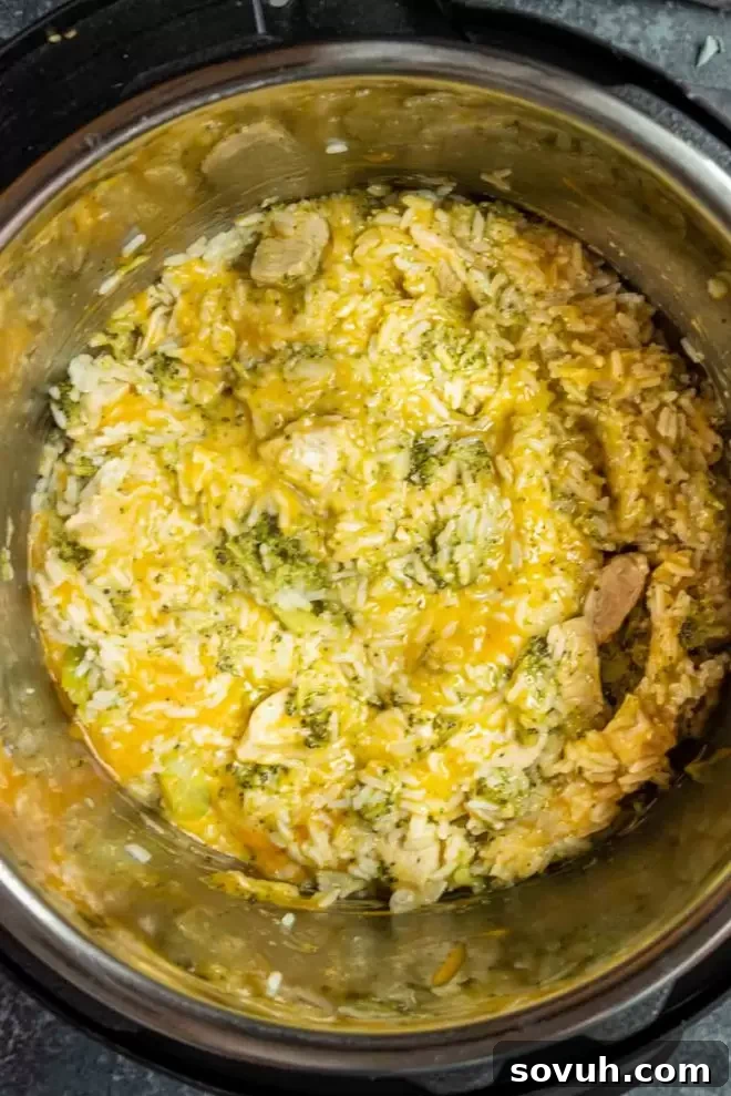 Cheesy Instant Pot Chicken and Rice cooking inside the Instant Pot, showing the steam and rich texture.