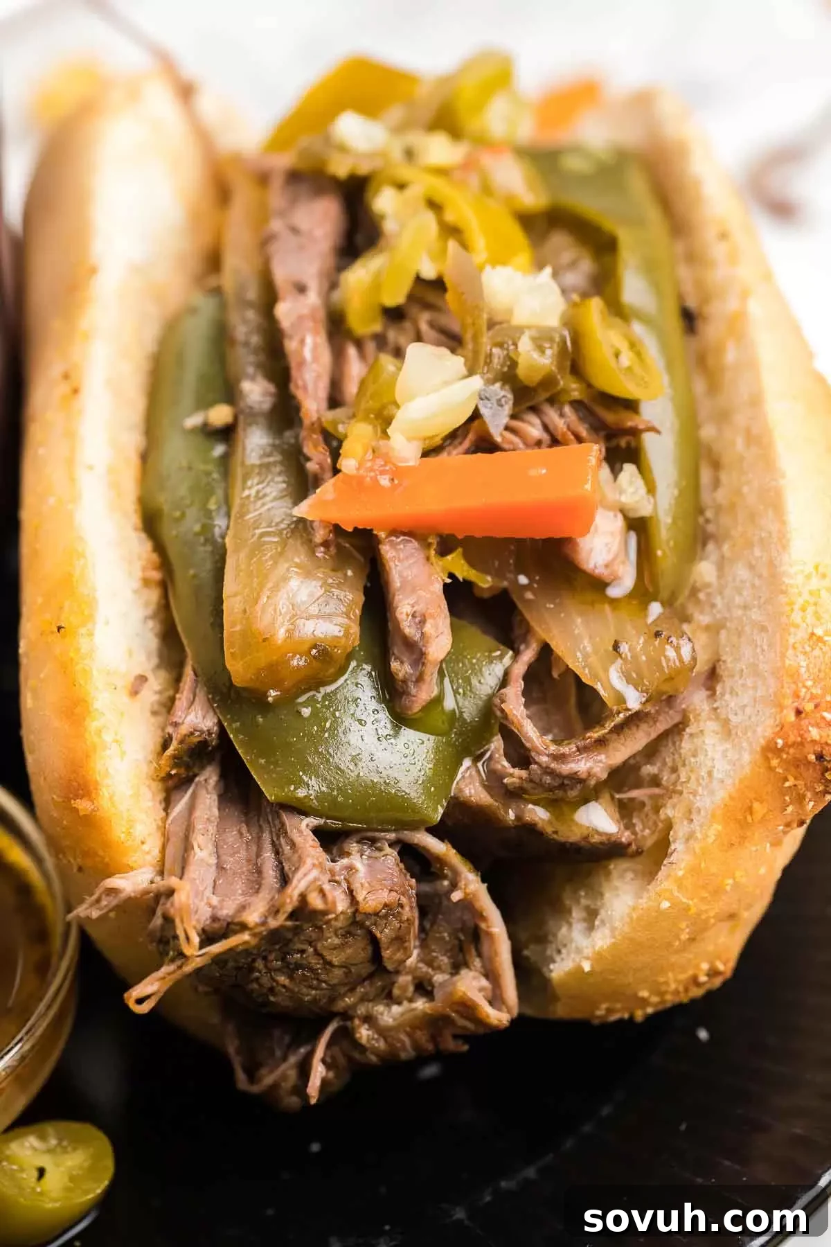Crock Pot Italian Beef sandwich served with giardiniera peppers.