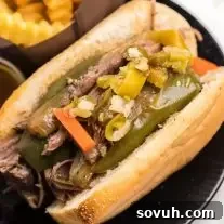 A close-up of a slow-cooked Italian beef sandwich topped with giardiniera and onions.