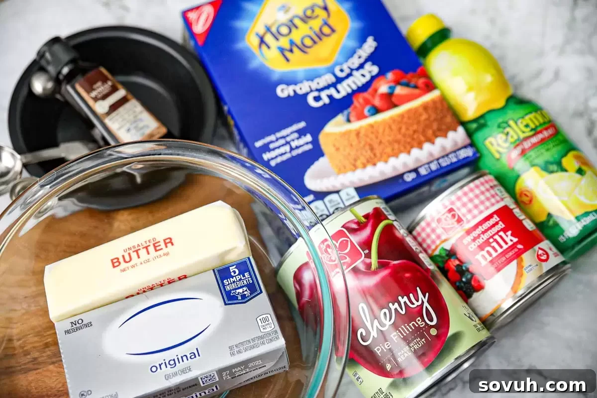 Ingredients for making No Bake Cherry Cheesecakes laid out on a table, including graham crackers, cream cheese, sweetened condensed milk, and cherry pie filling.