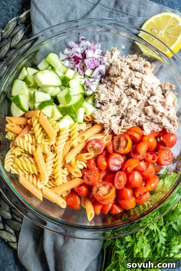 Fresh ingredients for tuna pasta salad in a glass bowl, ready to be mixed