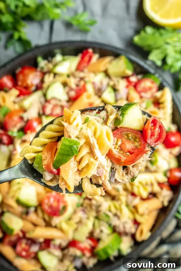 A spoonful of fresh tuna pasta salad being served from a bowl