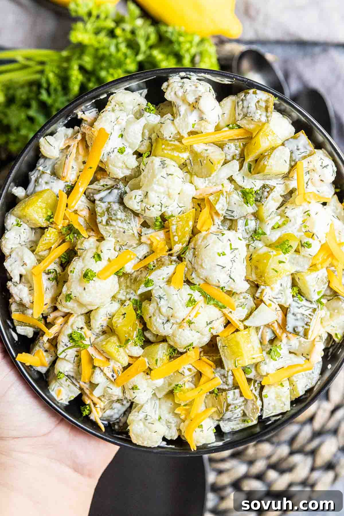 holding a bowl of Keto Dill Pickle Salad